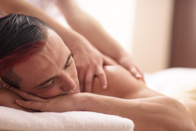 Positive young man having a back massage in a spa center