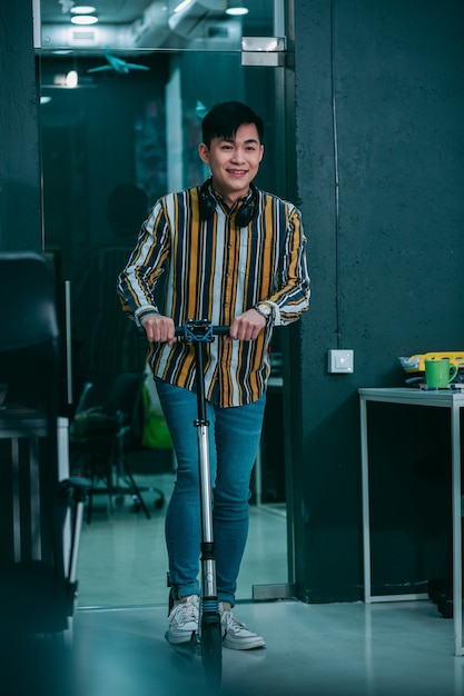 Positive young man smiling and riding a scooter indoors