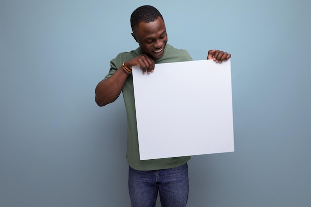 positive young smart american man in tshirt showing white screen with mockup for information