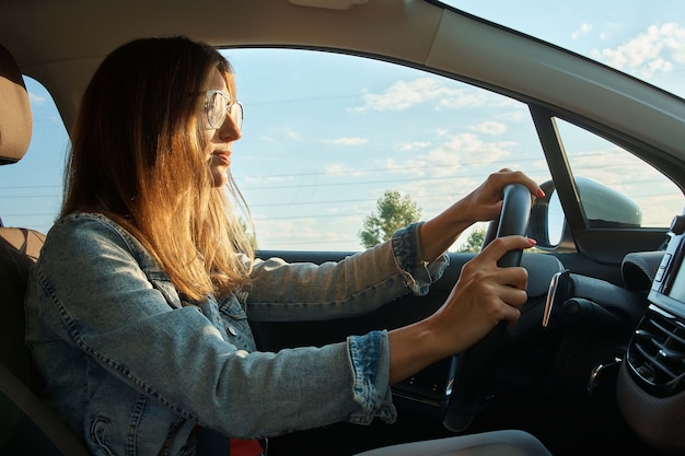 차를 운전하는 긍정적 인 젊은 여자.