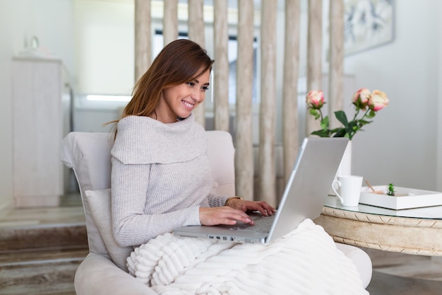 Positive young woman freelancer watching video in blog on netbook and having a coffee at comfortable home. Beautiful young business woman working on laptop.Freelancer connecting to internet