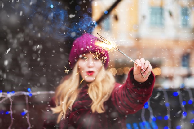 Positive young woman playing with the sparklers at the central city square