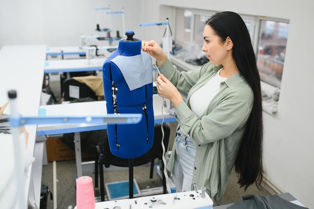 Positivo giovane donna che cuce con macchina professionale in officina