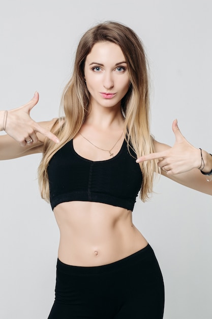 Positivity sporty girl pointing by finger on black top.