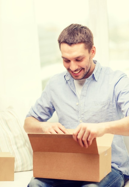 post, home and lifestyle concept - smiling man with cardboard boxes at home