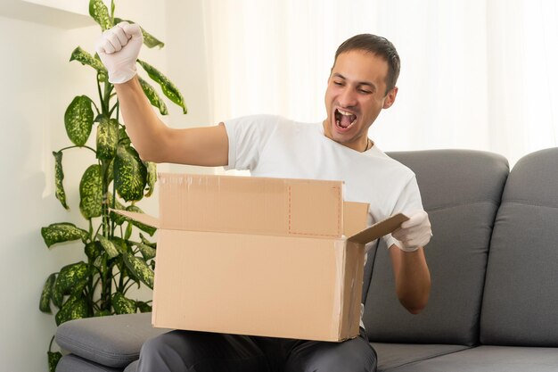 post, home and lifestyle concept - smiling man with cardboard boxes at home