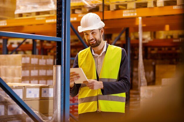 Postbode. Blij gelukkig man met behulp van een tablet tijdens het kiezen van een doos voor bezorging