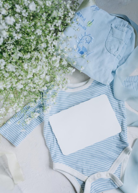 postcard mockup on the background of baby newborn clothes in blue colors