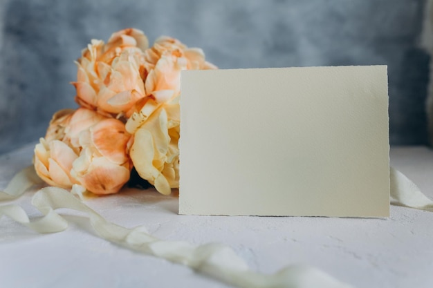 Postcard mockup on the background of peonies flowers on a light background