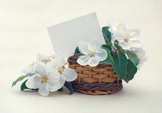 Cartolina con un delicato bouquet di fiori di mela in un cesto di vimini con spazio per la copia Foto Premium