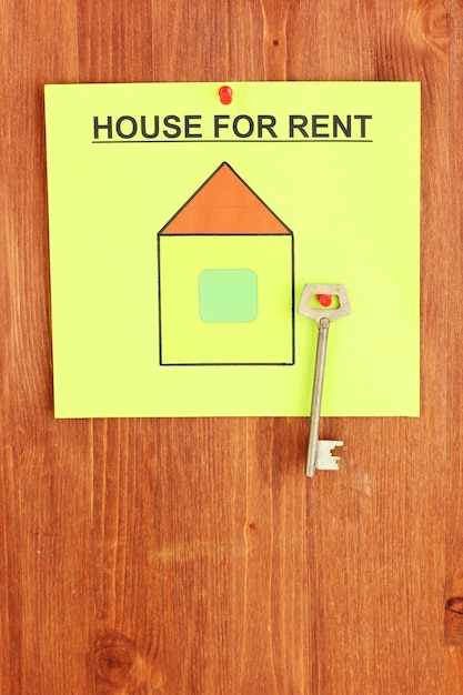 Photo poster about renting the house with the key on wooden background