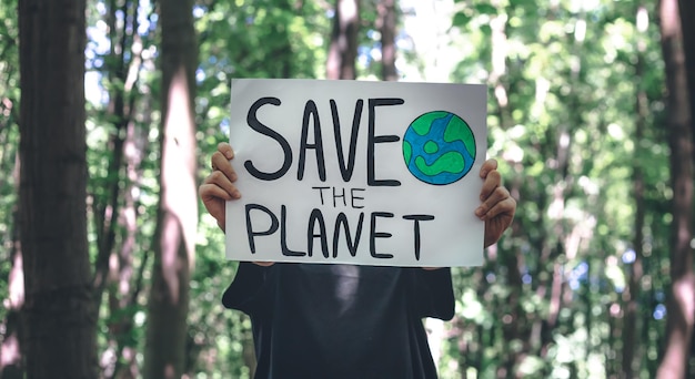 Poster in the call to save the planet in female hands in the forest