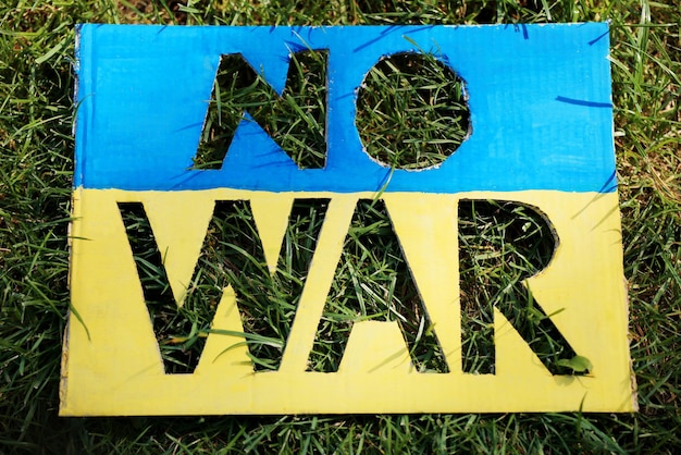 ビューの上の緑の草に「戦争はありません」という言葉でウクライナの旗の色のポスター
