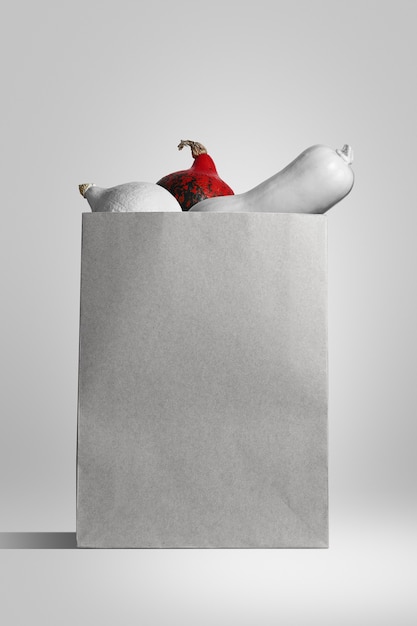 사진 흰색 배경에 흰색과 주황색 호박이 들어 있는 흰색 종이 가방을 보여주는 포스터