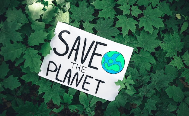 Poster with the inscription save the planet in the forest among the plants