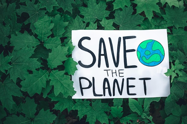 Poster with the inscription save the planet in the forest among the plants