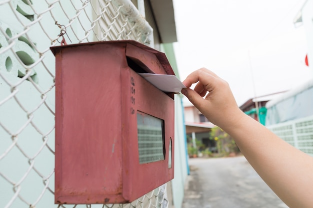 Photo posting a letter to red british postbox on street,