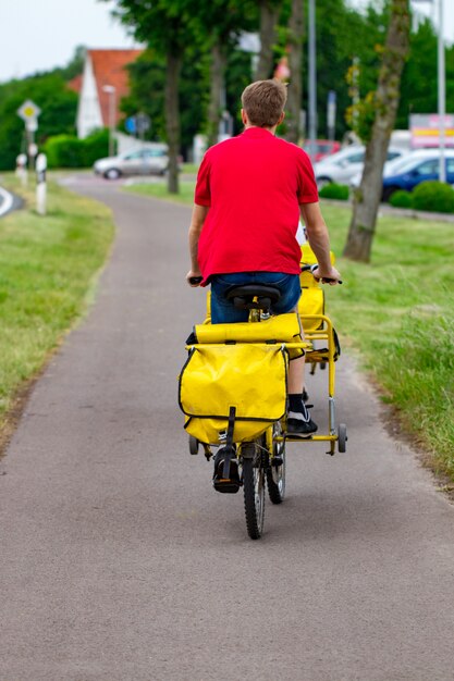 近所で郵便を運ぶ彼の貨物自転車に乗る郵便配達員。