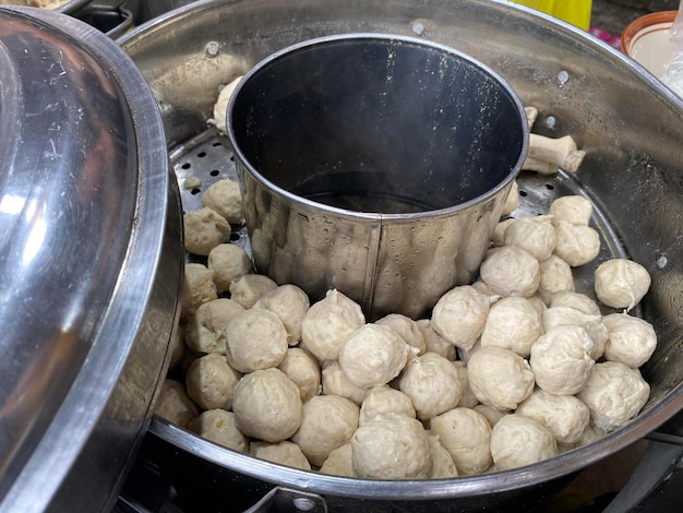 A pot of dumplings with a small bowl of meatballs.