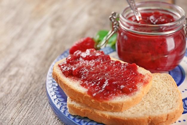 Foto pot en brood met aardbeienjam op plaat