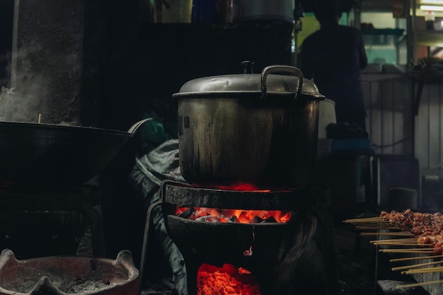 a pot of food is cooking on a stove with a lot of smoke and fire in a traditional kitchen