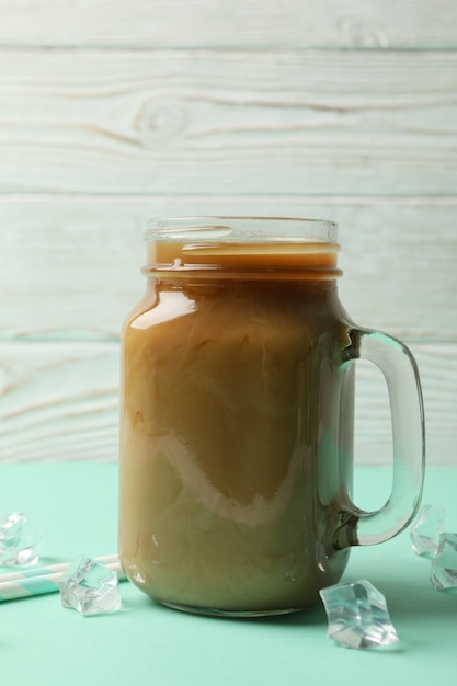 Pot ijs koffie, ijsblokjes en rietjes op mint tafel