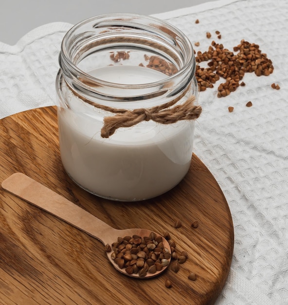 Pot met alternatieve boekweitmelk op een houten bord. Diervriendelijk veganistisch eten.