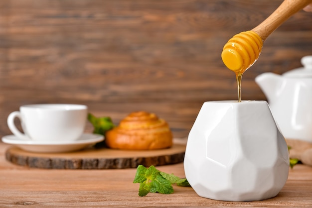 Pot met lekkere honing op houten tafel