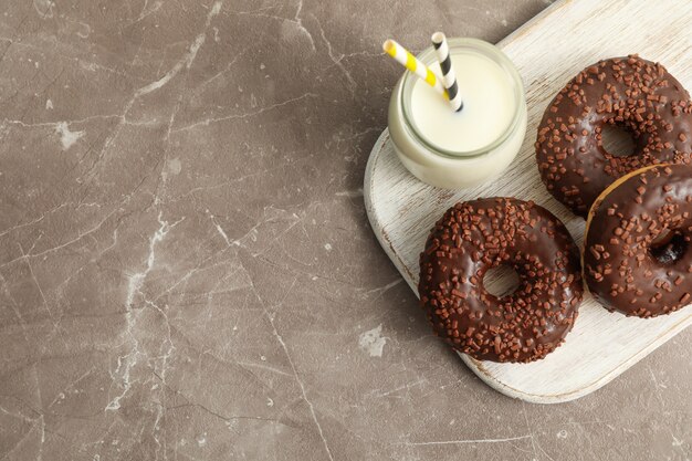 Pot met melk en smakelijke donuts op grijze tafel