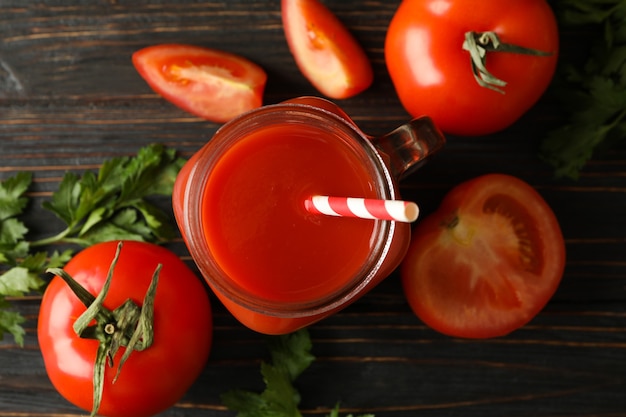 Pot met tomatensap, tomaten en peterselie op een houten bord