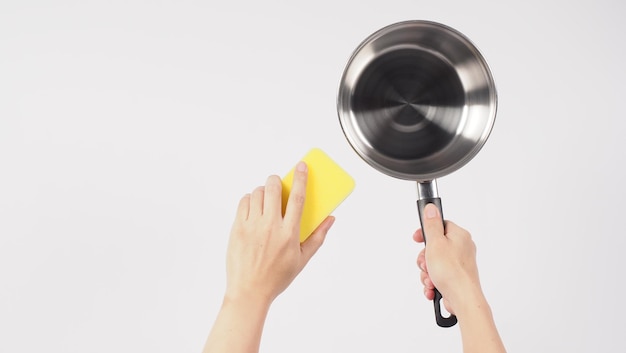 Pot schoonmaken. Man hand op witte achtergrond die de non-stick pot schoonmaakt met een handige afwasspons die gele kleur heeft aan de zachte kant en groen aan de harde kant voor hygiëne na het koken. Elektrische pan.
