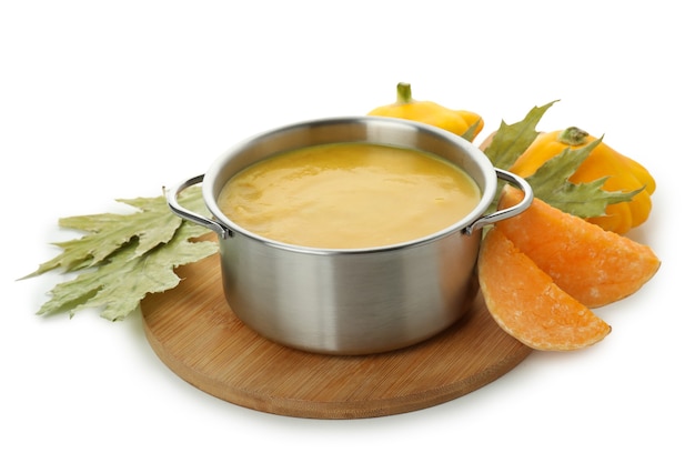 Pot with pumpkin soup and ingredients isolated on white background