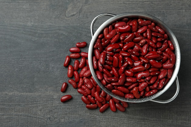 Pot with red beans on gray background