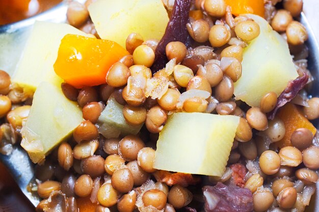 Potage of lentils with bacon in the pot with the metal saucepan to serve typical spanish food