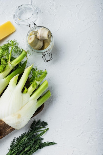 Ingredienti per patate e carciofi al forno, su sfondo bianco testurizzato, vista dall'alto con spazio per il testo