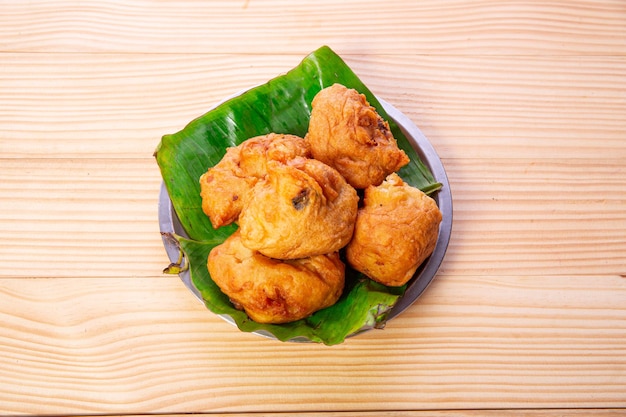 Potato bonda snack piccante indiano disposto in una piastra d'acciaio rivestita di foglia di banana