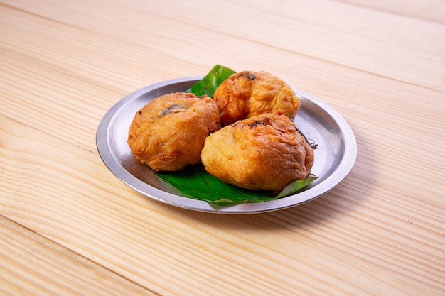 Potato bonda snack piccante indiano disposto in una piastra d'acciaio rivestita di foglia di banana