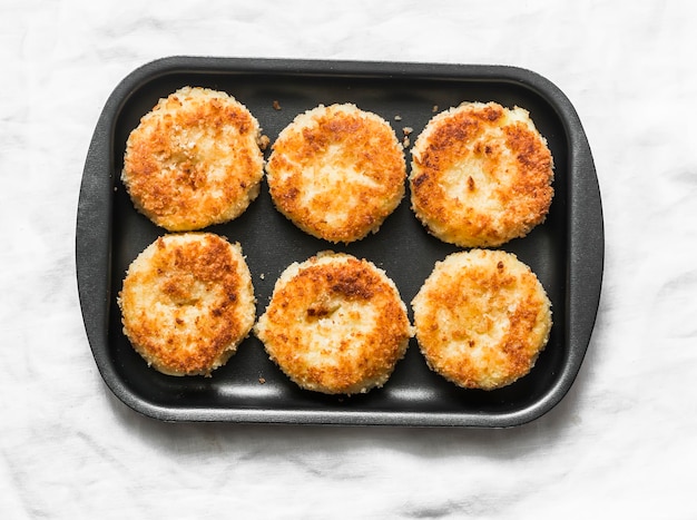 Potato bread crumbs baked cakes on a baking tray on a light background top view