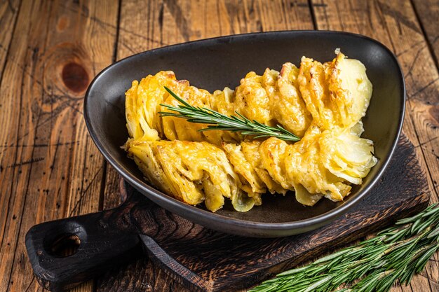 Potato casserole Gratin in a plate with herbs. wooden background. Top View.