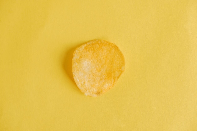 Potato chip on a yellow background. Top view. Copy, empty space for text