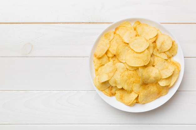 Картофельные чипсы в миске на цветном фоне Вкусные хрустящие картофельные чипсы в миске Место для текста Вид сверху