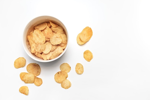 Potato chips and bowl on white background Junk food concept Top view Flat lay