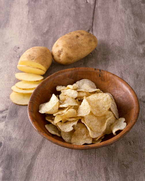 Potato chips on a bowl with raw potato