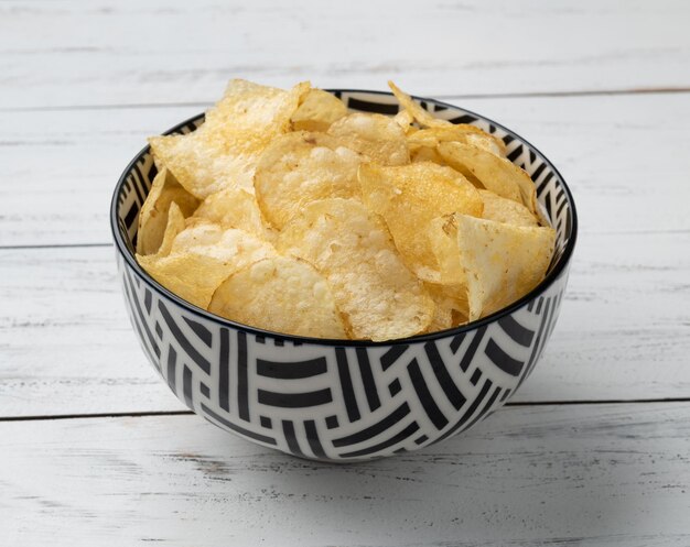 Potato chips in a bowl over wooden table