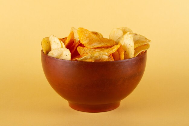 Potato chips in clay bowl isolated on beige background side view