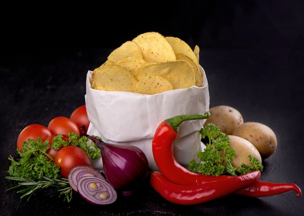 Potato chips on a dark wooden board.