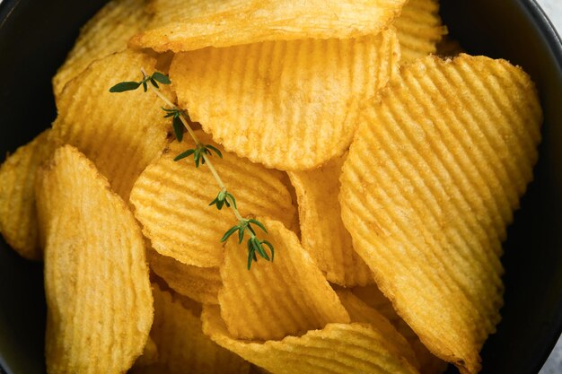 Potato chips Fast food Crispy potato chips ceramic black bowl with sour cream sauce and onions in wooden stand on gray kitchen table concrete background American tradition Hot BBQ Top view