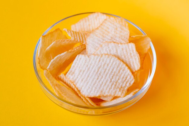 Potato chips in glass bowls on yellow background Junk unhealthy food chips party food fast food