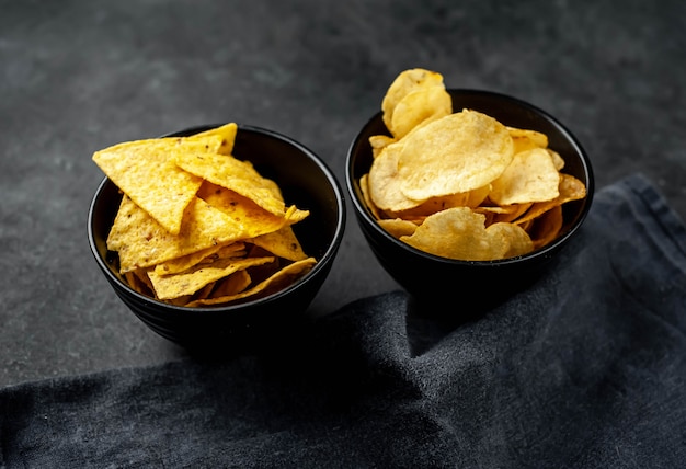 Potato chips and nachos in black bowls