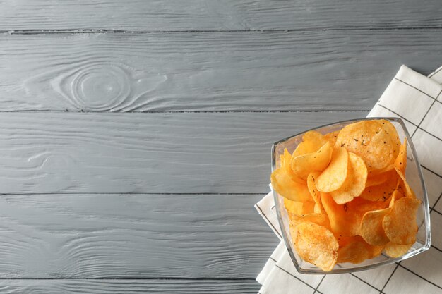 Potato chips, napkin on grey wooden, space for text. Top view